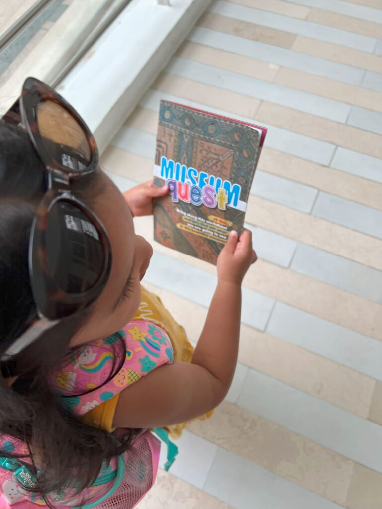 A toddler holds the Museum Quest booklet at Islamic Arts Museum Malaysia.