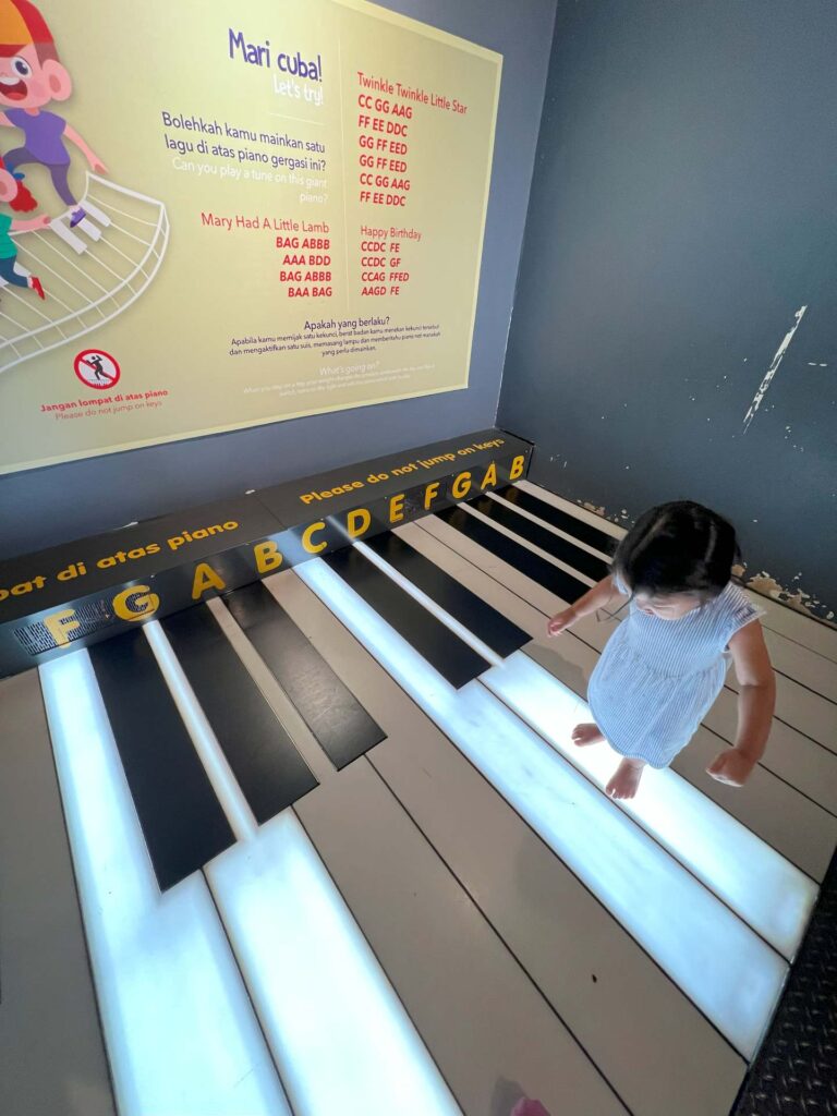 A young girl steps on a light-up floor piano at national science center kuala lumpur.