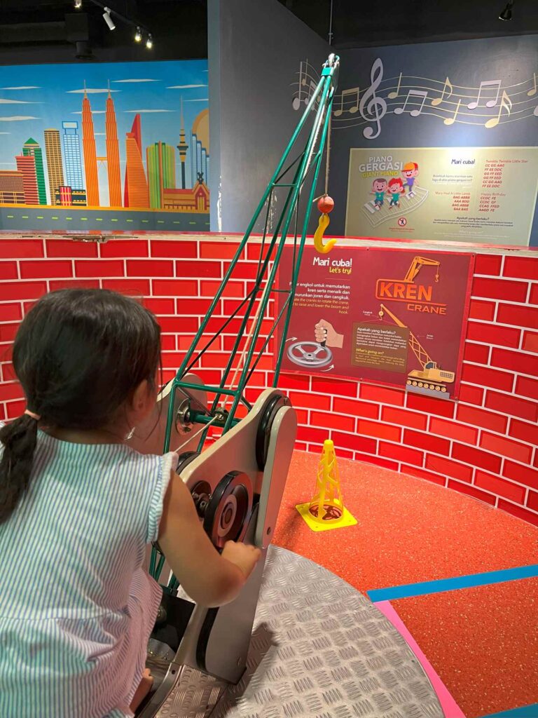 A toddler plays with a crane exhibit at Kuala Lumpur Science Museum.