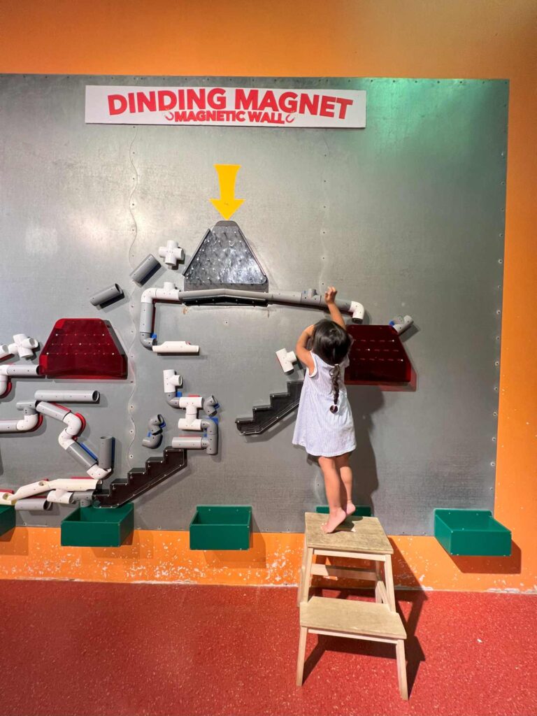 A girl tries out one of the National Science Museum's toddlers activities in KL - a magnet wall with connecting pipes.