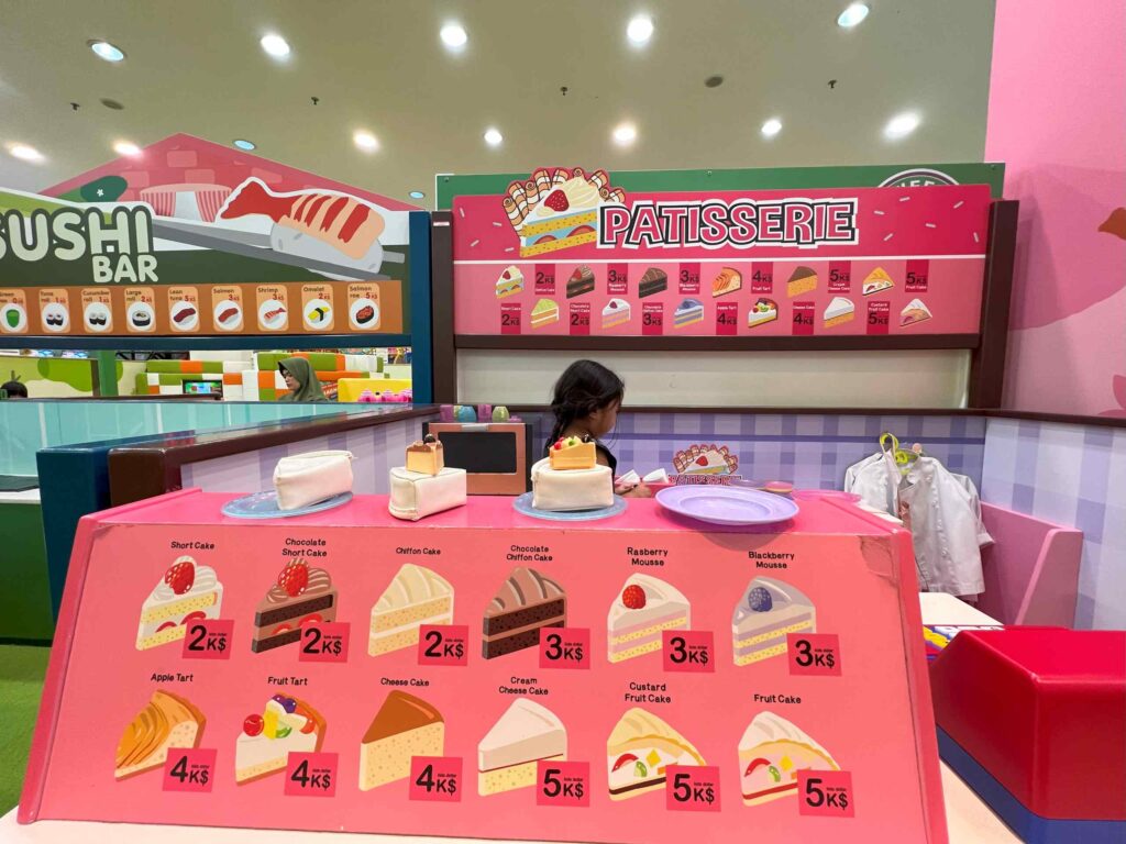 A toddler runs a pretend cake stall at Kidzoona AEON Mall Shah Alam.