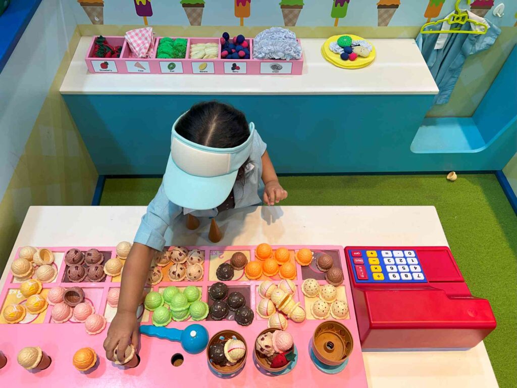 A toddler runs a pretend ice cream stall at Kidzoona AEON Mall Shah Alam.