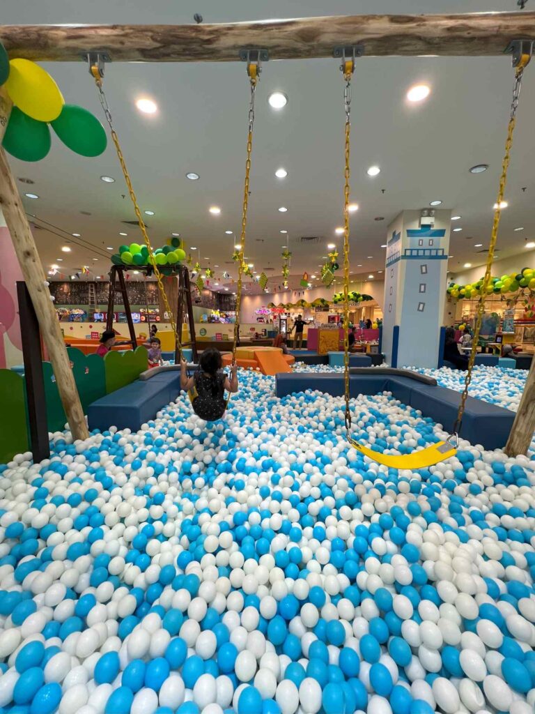 A toddler plays on the swings in a ball pit at Kidzoona AEON Mall Shah Alam.