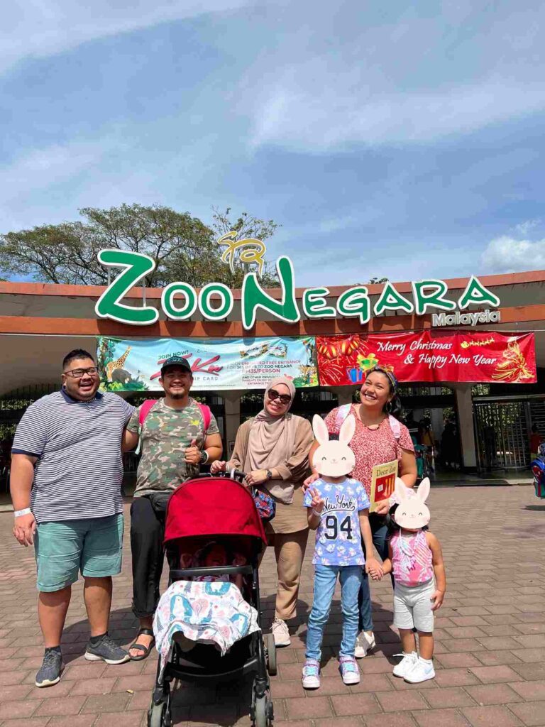 Families posing for a photo at Zoo Negara, a great place to explore Kuala Lumpur with toddlers.
